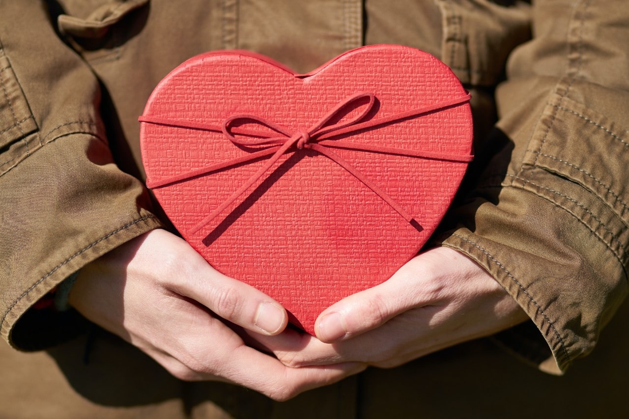 A person holding a red Valentine heart ready to give to their love
