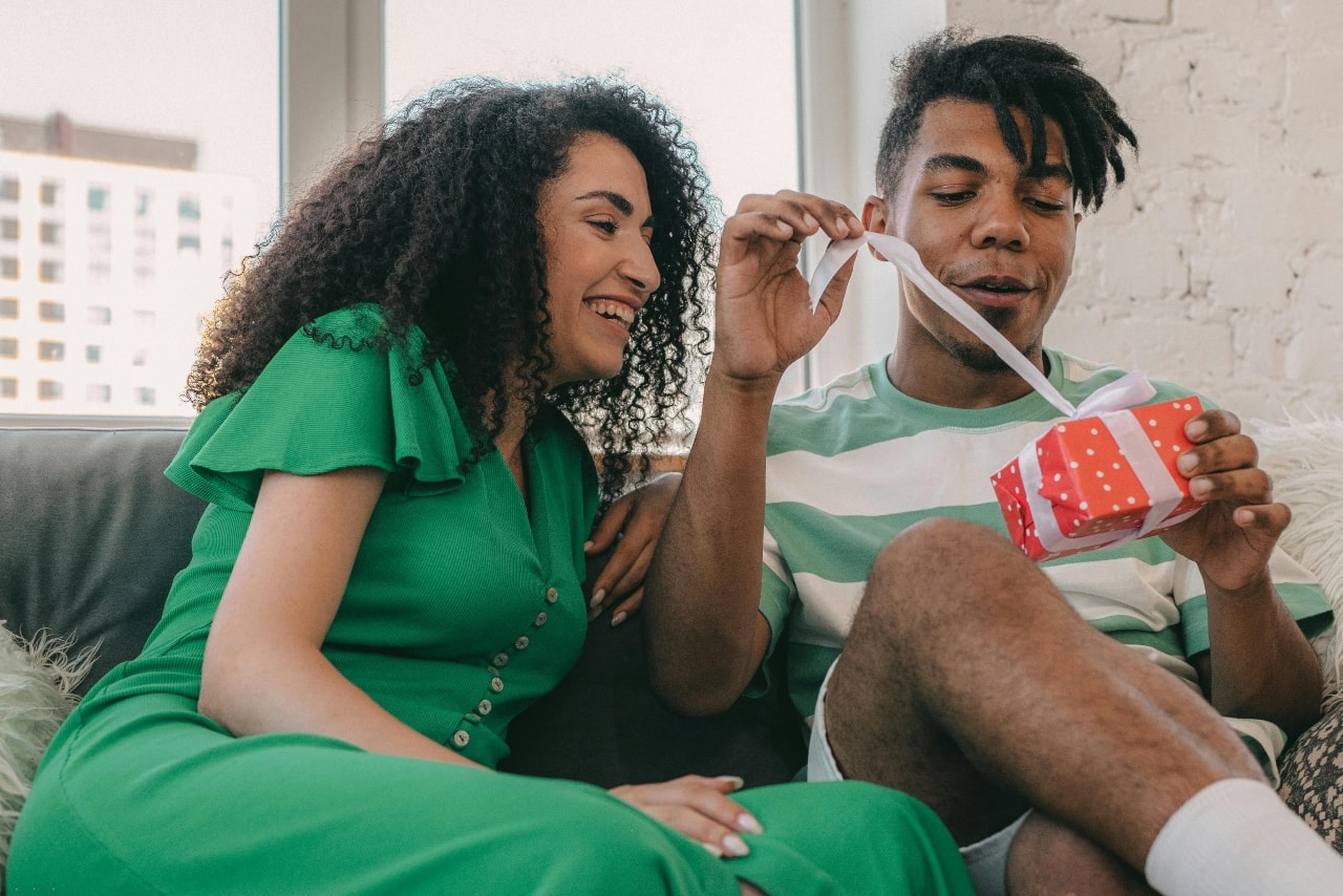 A man opening a Christmas present with his lady