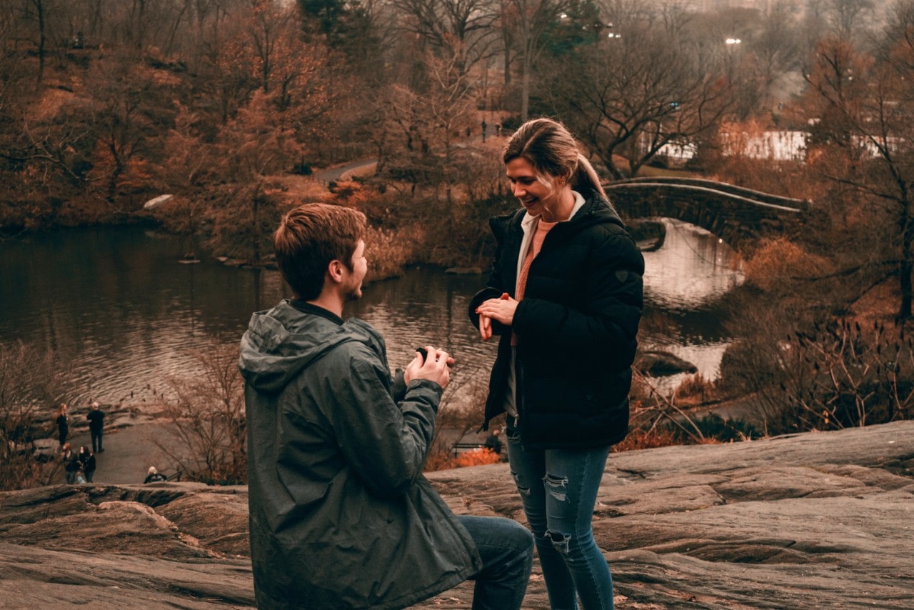 A man proposing to his partner amid a picturesque lake during the winter.