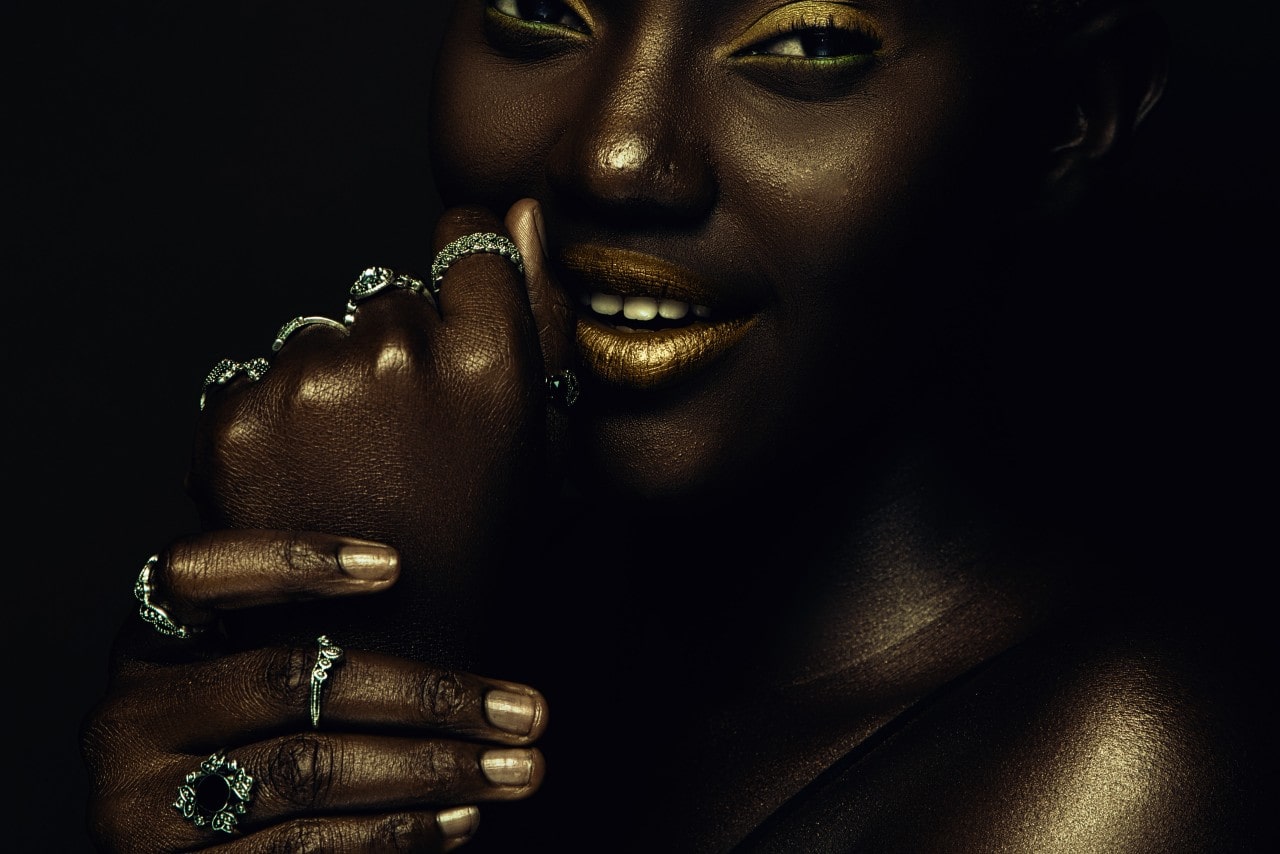 a woman wearing shimmery gold makeup and a stack of silver fashion rings