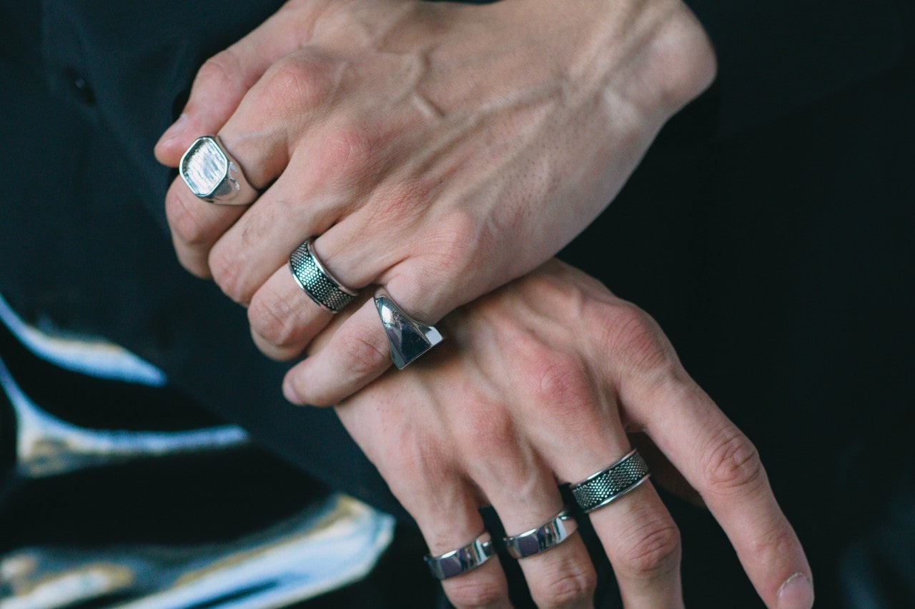 a man’s hand wearing a selection of thick, bold silver fashion rings