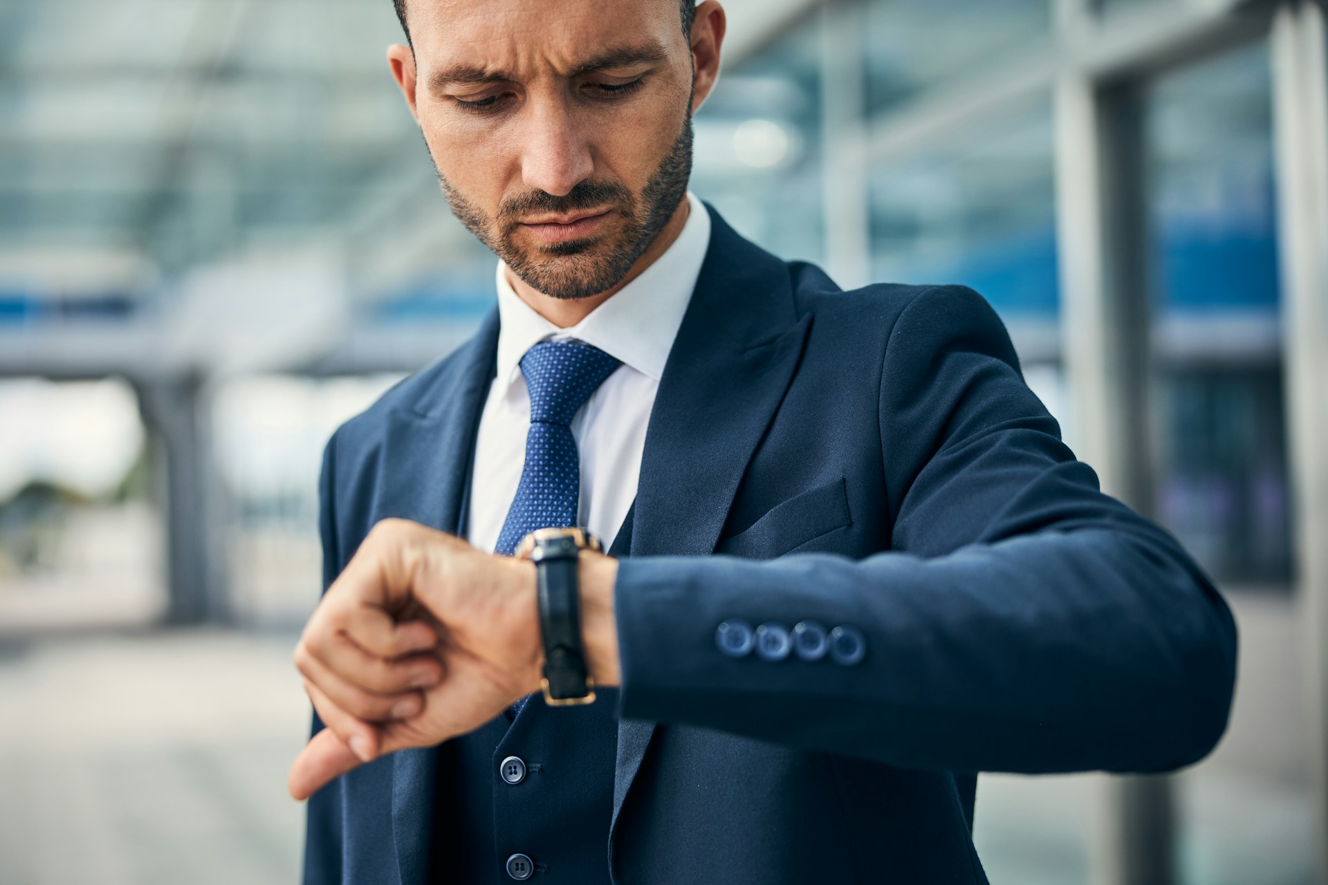 a man in a blue suit looking down at his dress watch