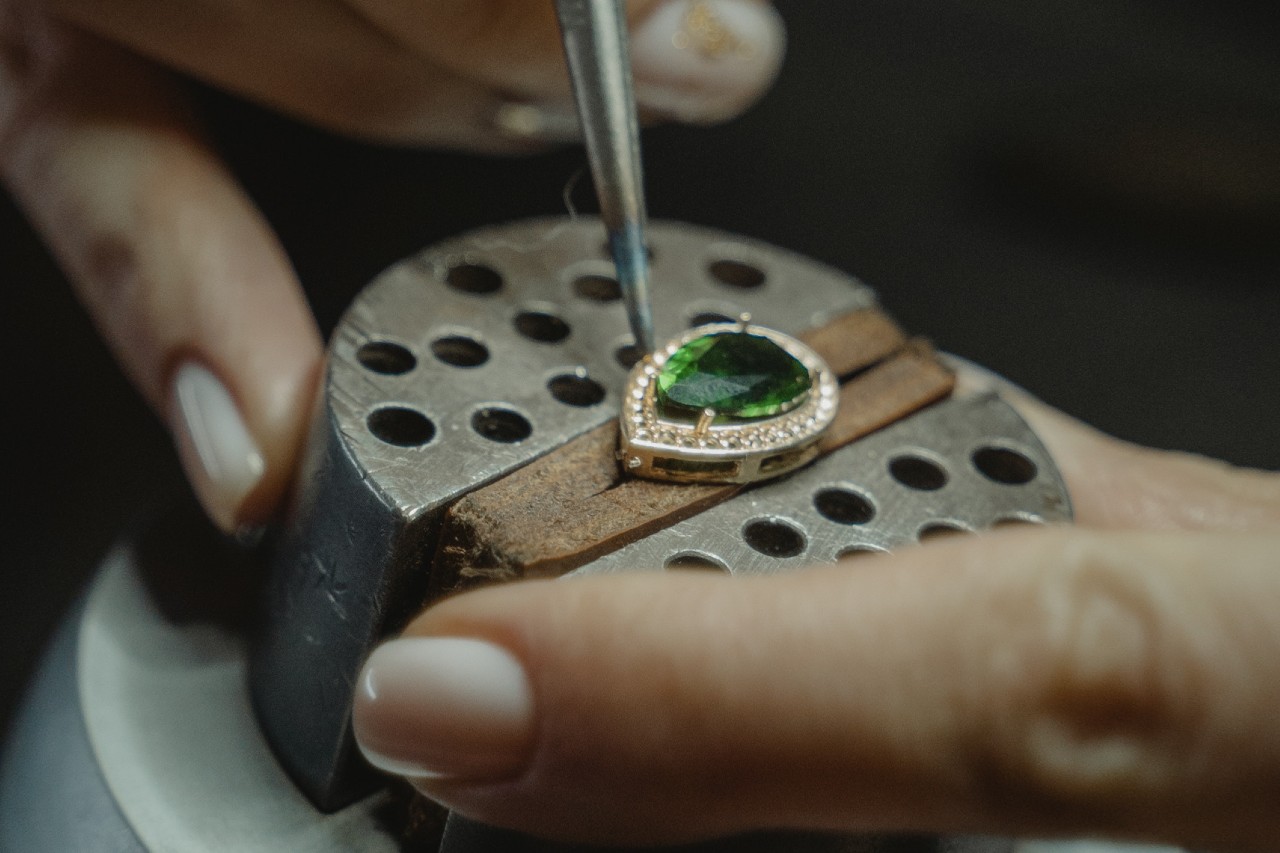 An emerald having prongs set around it with smaller diamonds around the verdant stone; Rottermond Jewelers custom design jewelry opens a world of possibilities.