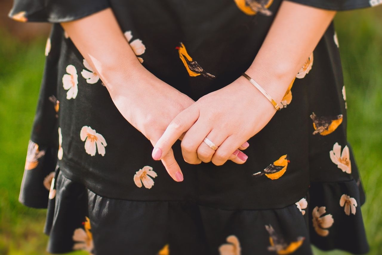 A close-up of a young woman wearing a simple and dainty bracelet and ring.