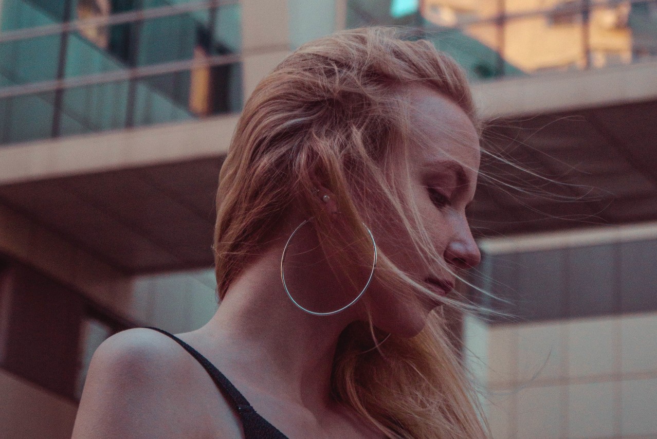 A close-up of a young woman wearing a large but dainty pair of hoop earrings.