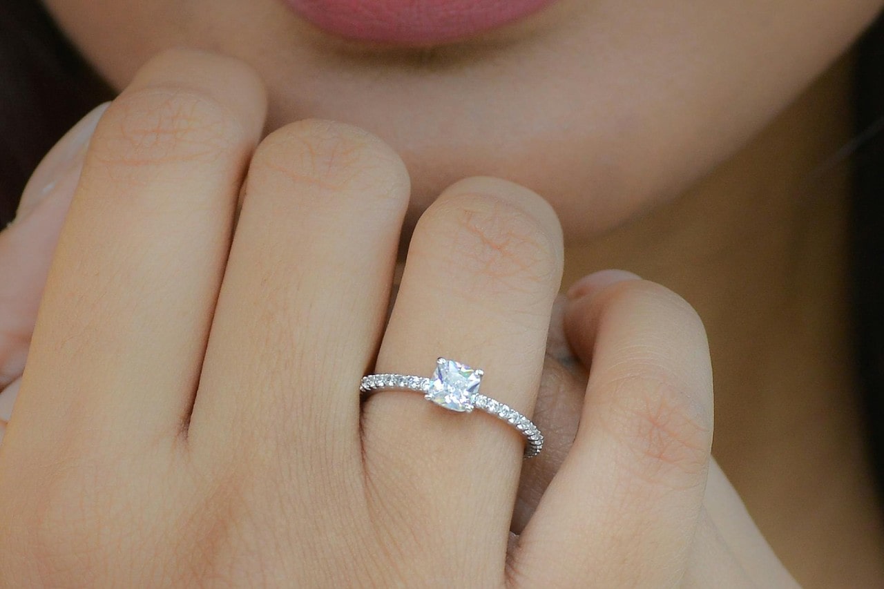 close up image of a woman’s hand wearing a white gold diamond engagement ring