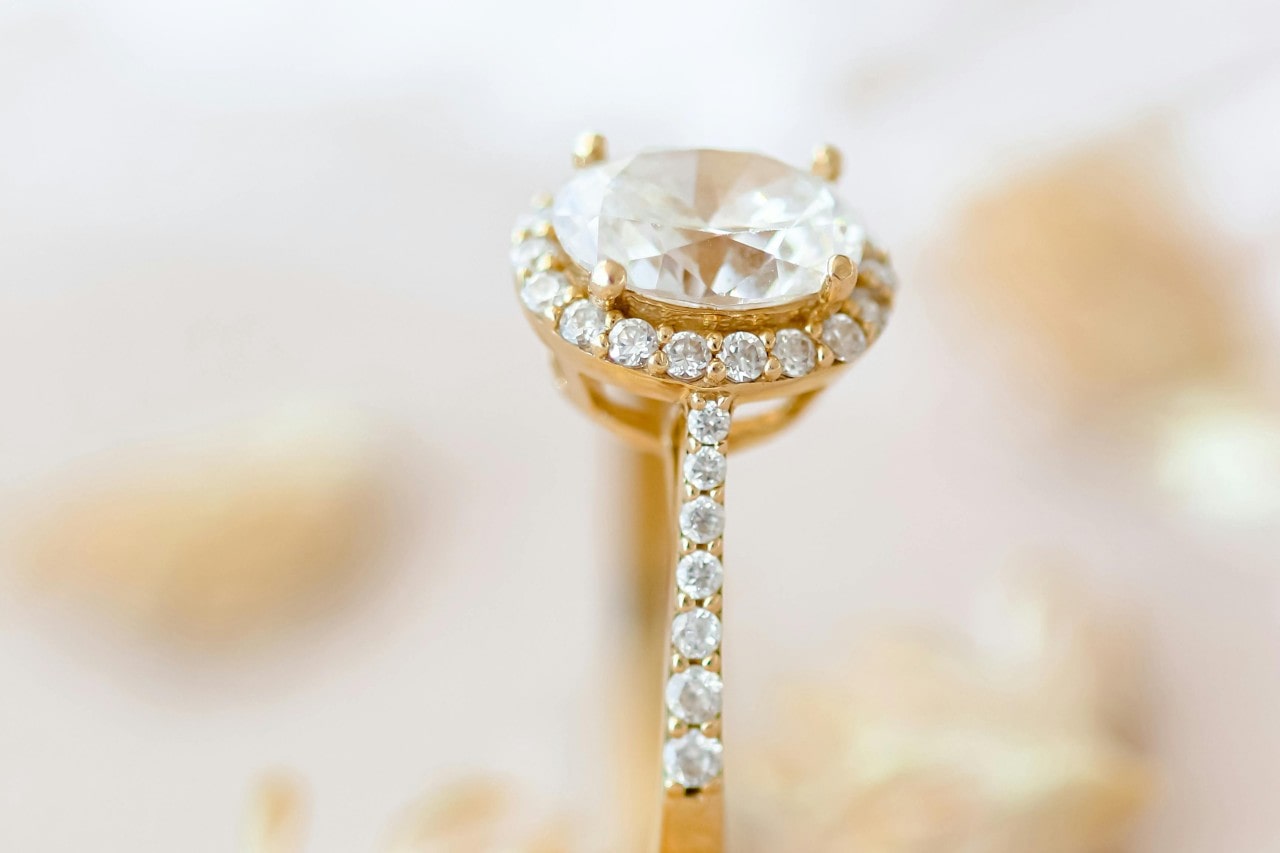 close up image of a yellow gold diamond engagement ring with a halo and side stones