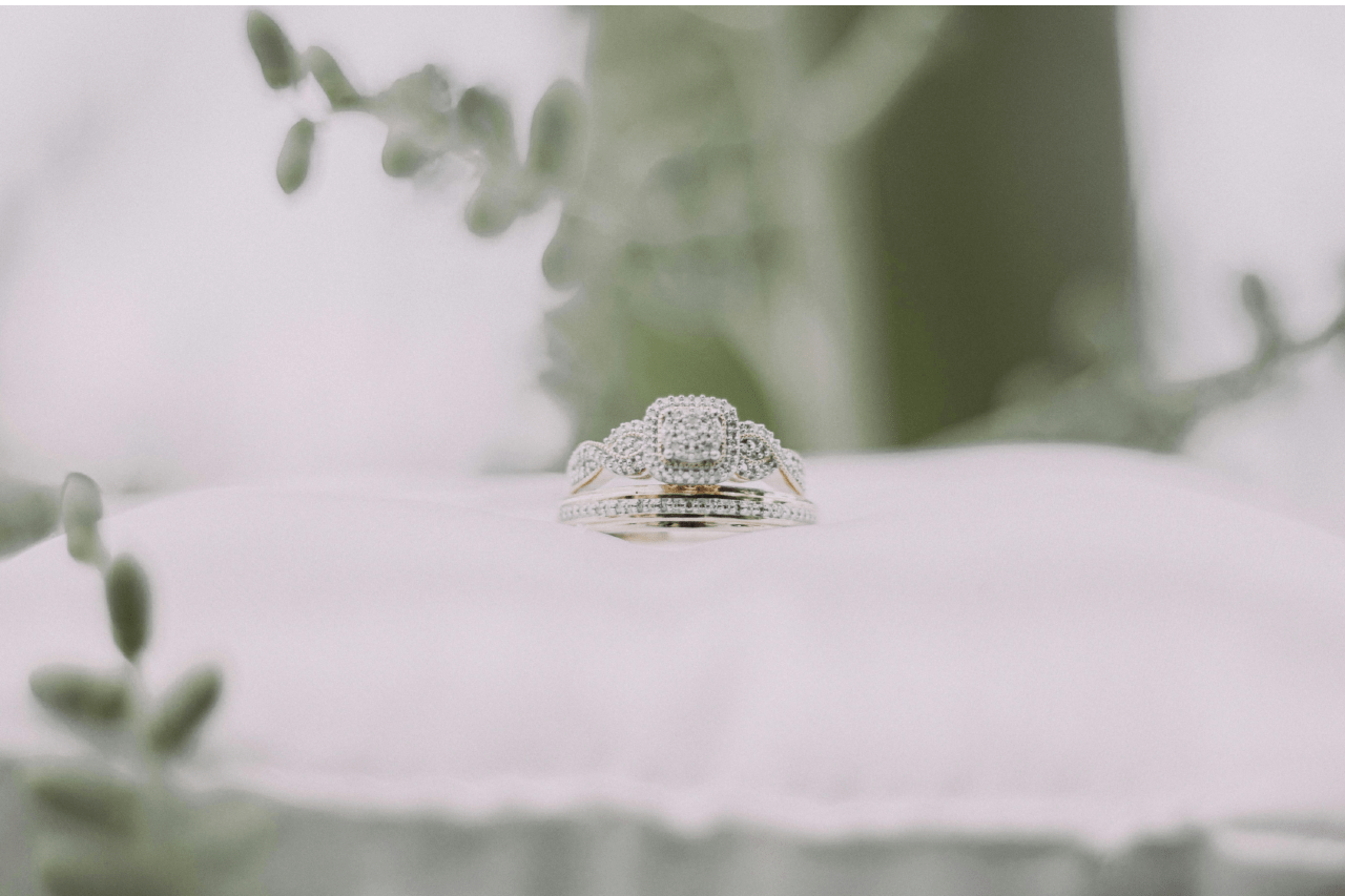 a matching engagement ring and wedding band set on a white pillow.