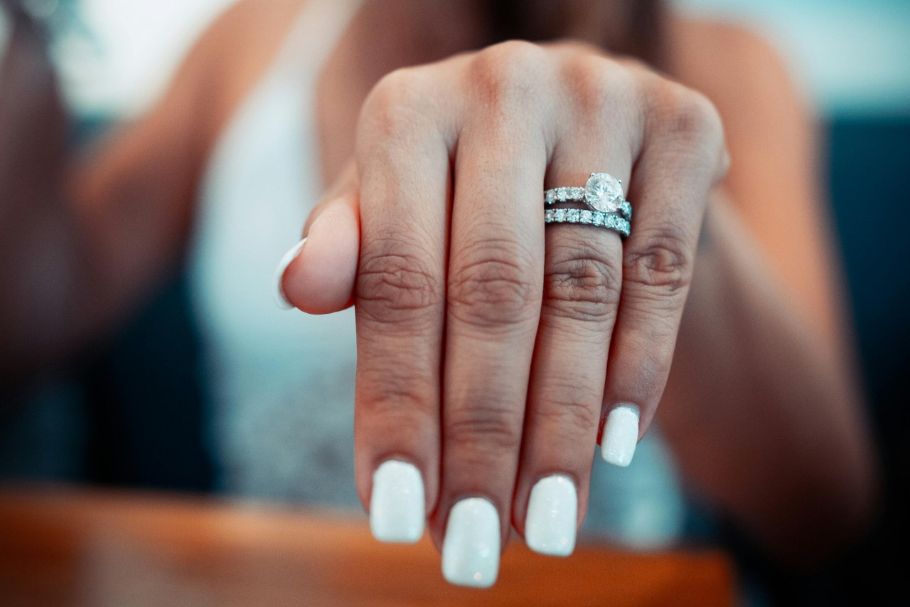 a woman’s extended hand, showing off a matching engagement ring and wedding band set