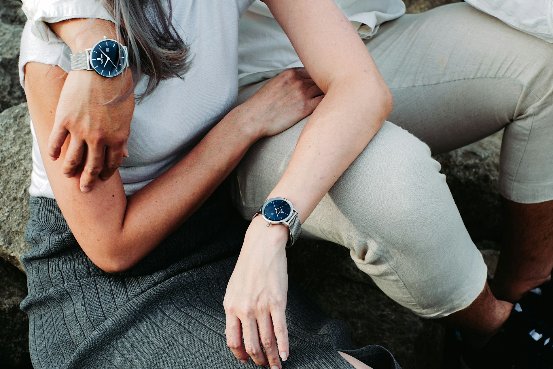 a couple embracing and wearing matching watches with blue dials