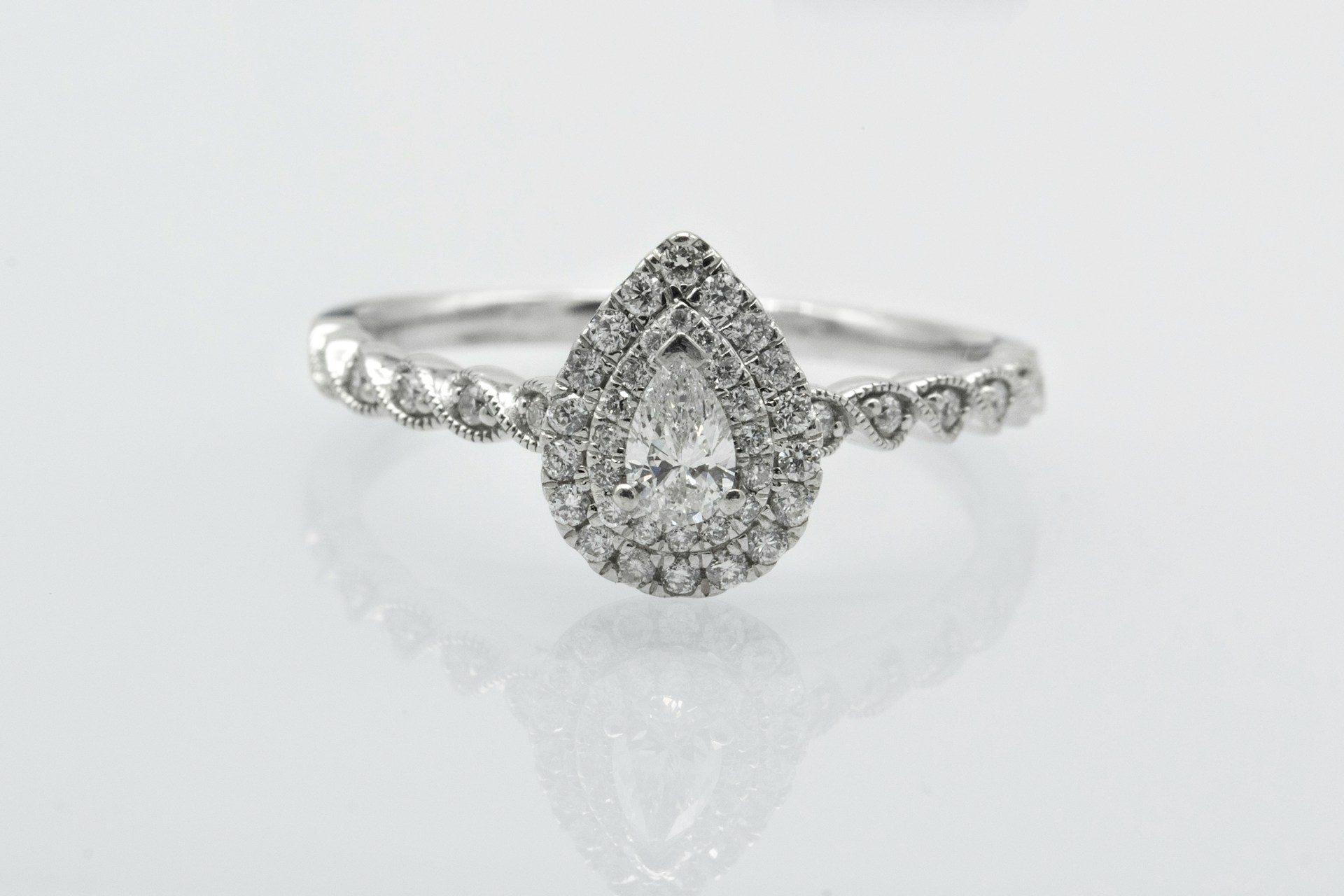 a vintage-inspired engagement ring with a pear shaped center stone and double halo